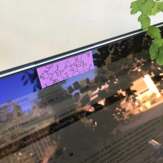 Picture of doodled on post-it note covering the camera on a laptop