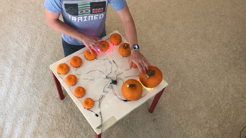 a series of pumpkins of decreasing size arranges around a table with wires leading back to a raspberryPi computer