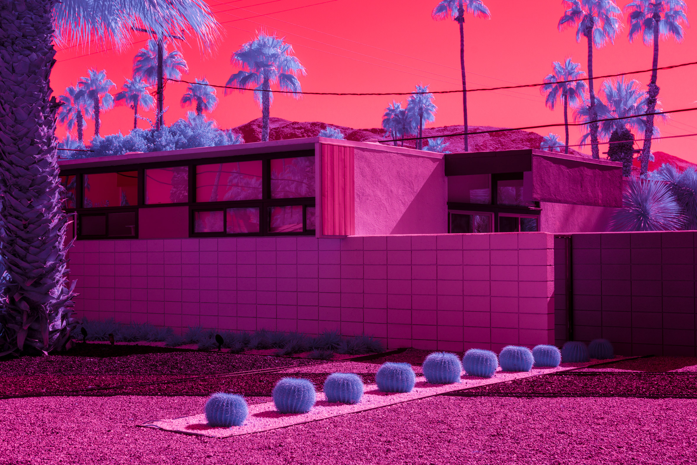 a modernist house in a desert lanscape surrouned by pinks and blues and purples.