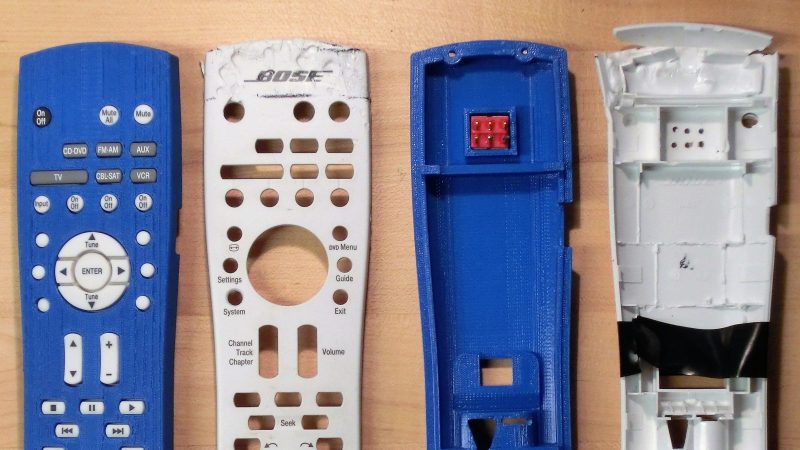 Two sets of a face plate and back plate of a TV remote control. One is white with chew marks, the other is blue and 3D printed.