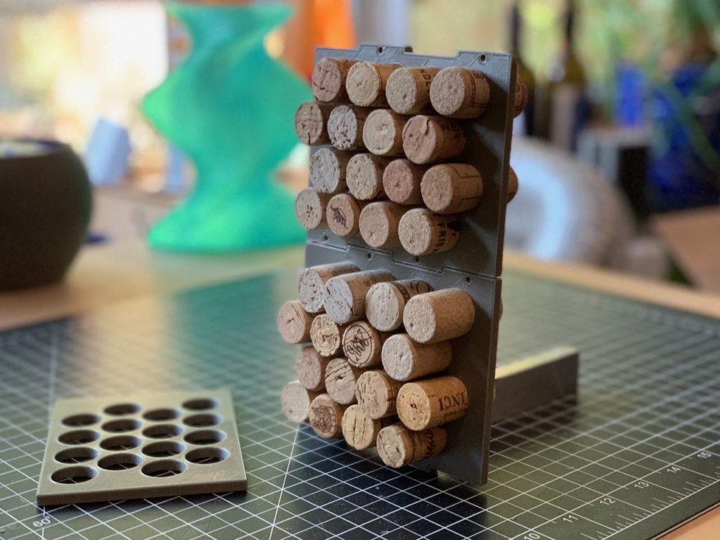 wine corks slotted perpendicularly into a grey plastic panel with cork-sized holes in a compact grid