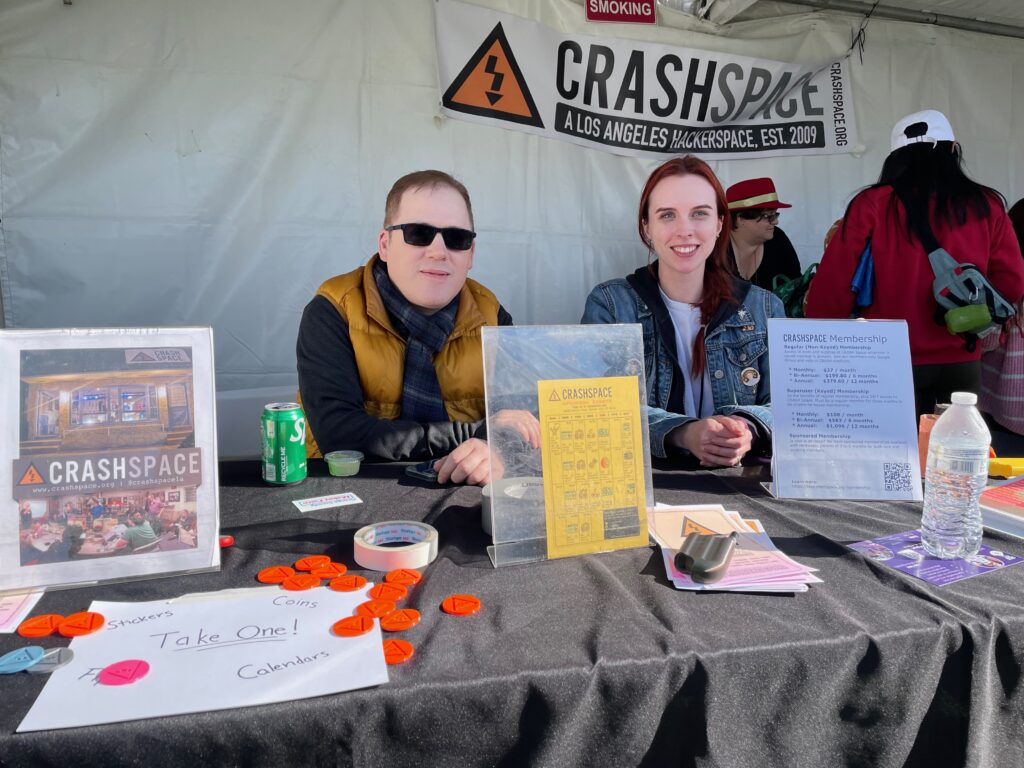 Two people sit at a table with a banner that says CRASH Space in the background.