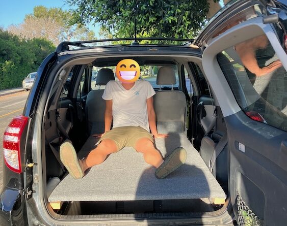 A sleeper and storage setup in the back of a Toyota RAV4.