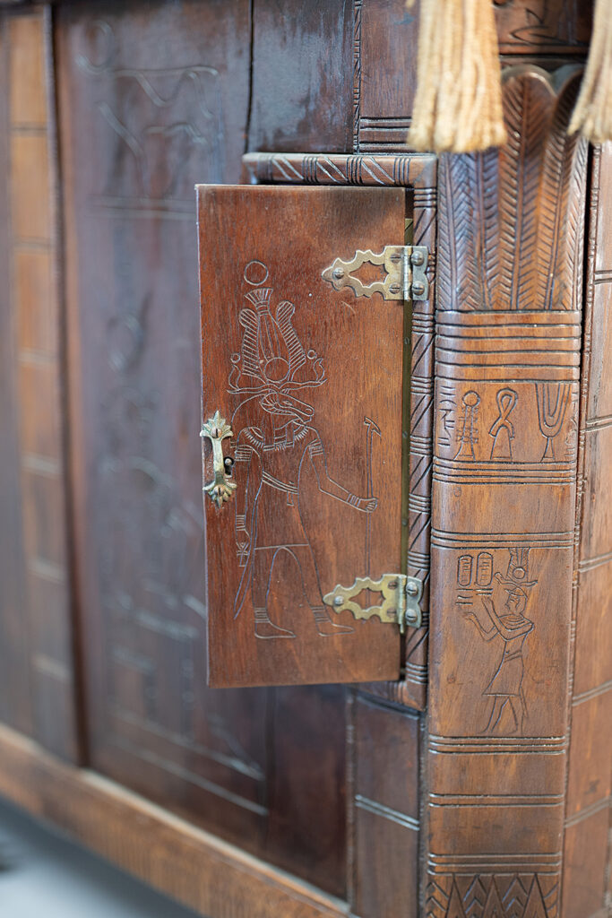 Detail view of the Egyptian-inspired carvings covering the cabinet
