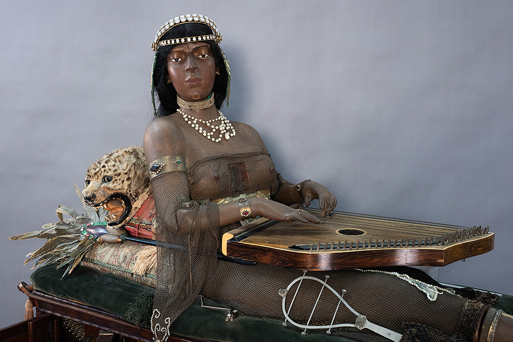 Closer image of Isis, her zither, and the head of her cat